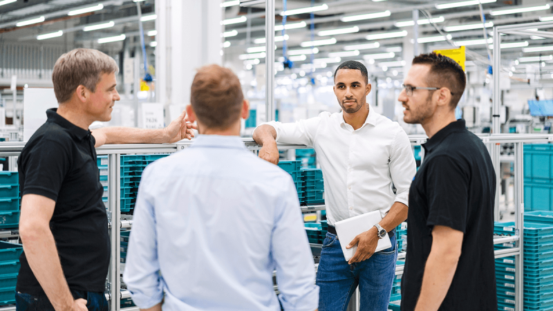 Industrial team discussing production processes on shopfloor in modern manufacturing facility.